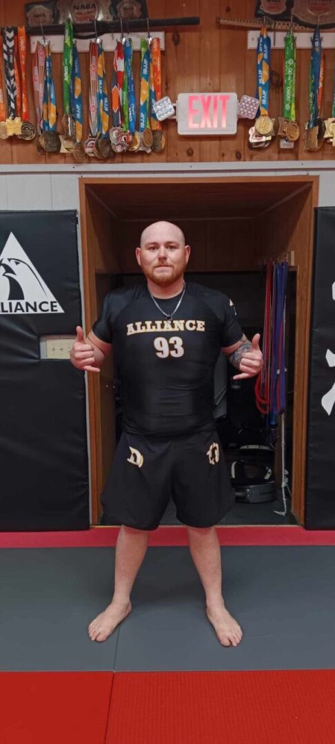 A man in black shirt and shorts standing next to wall.